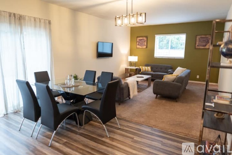 A living room with a dining table set up with chairs and a television on the wall.