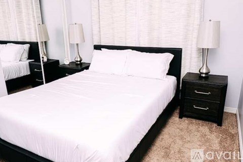 A bedroom with a large bed and two nightstands with lamps.