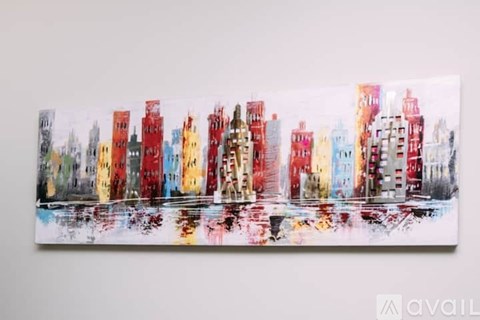 A painting of a cityscape with buildings in red, yellow, and blue.