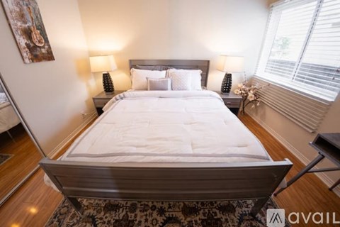 A bedroom with a large bed and two lamps on either side of the bed.