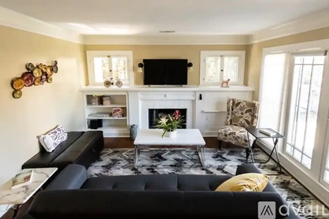 A living room with a black couch and a white fireplace.