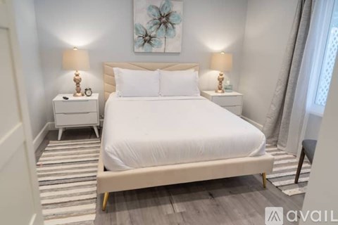 A bedroom with a large bed and two nightstands with lamps.