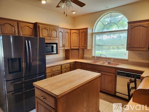 A kitchen with wooden cabinets and a stainless steel refrigerator.