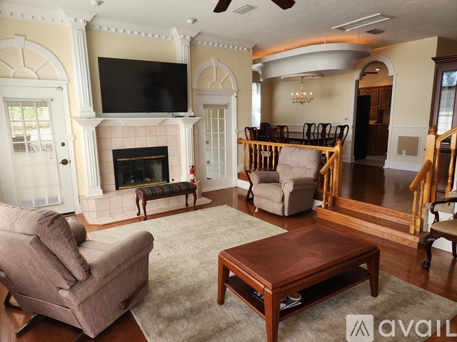 A living room with a fireplace and a television mounted above it.