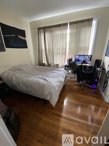 A bedroom with a bed, a desk with a computer and a chair.