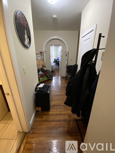 A hallway with a coat rack and a framed picture on the wall.