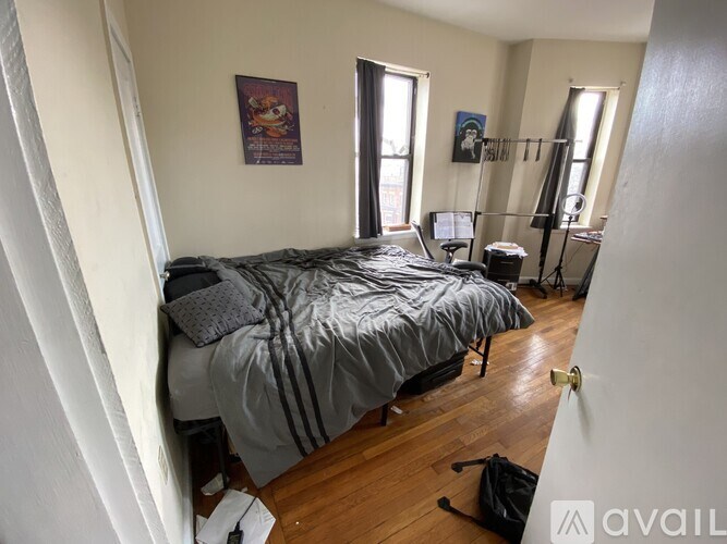 A bedroom with a bed, desk, chair, and two windows.