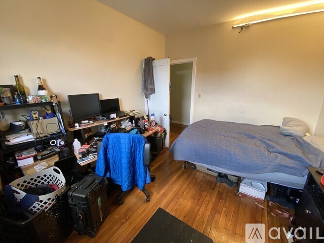 A room with a bed, desk, and computer equipment.