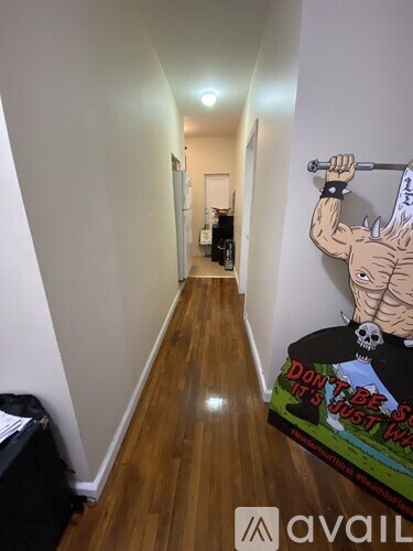 A hallway with a poster of a muscular man lifting a barbell and a skull wearing sunglasses.