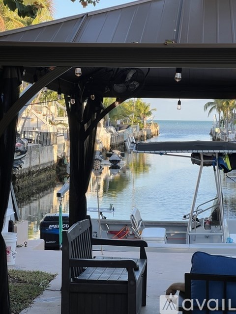 A boat is docked at a pier with a bench and table nearby.