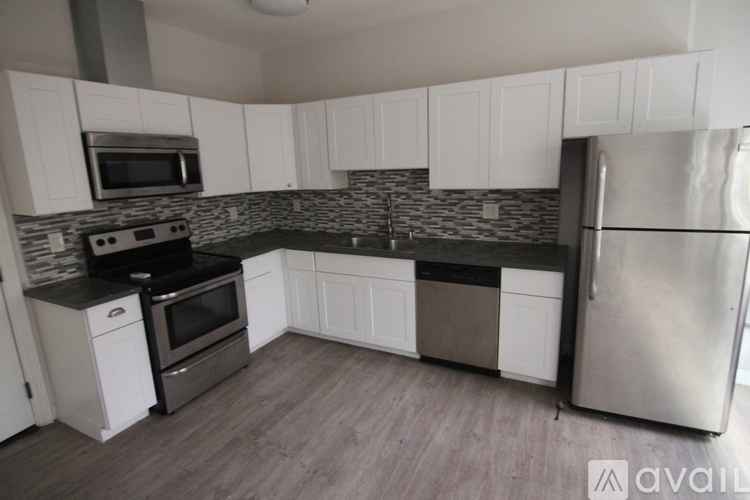 A kitchen with white cabinets and a black countertop.