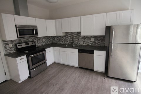 A kitchen with white cabinets and a black countertop.