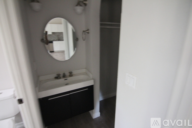 A bathroom with a mirror, sink, and toilet.