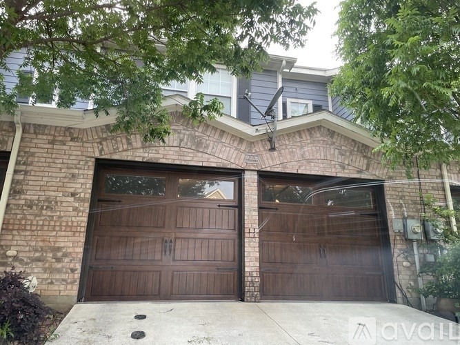 A house with a brown garage door and a brick wall.