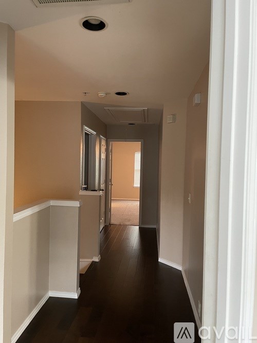 A long hallway with a white wall on the left and a door on the right.