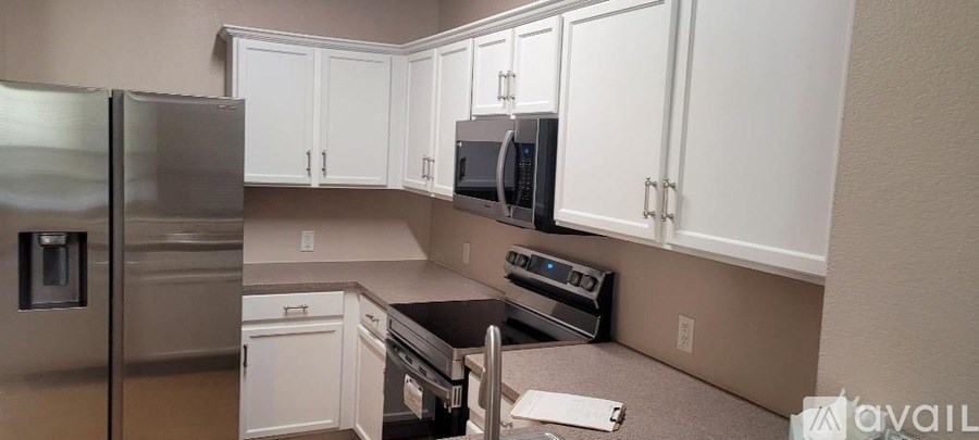 A kitchen with white cabinets and a stainless steel refrigerator.