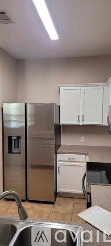 A kitchen with a stainless steel refrigerator and white cabinets.