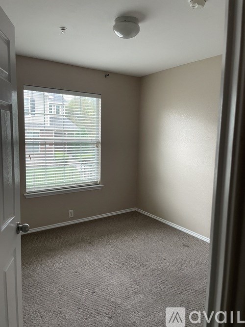 A room with a carpeted floor and a window with blinds.