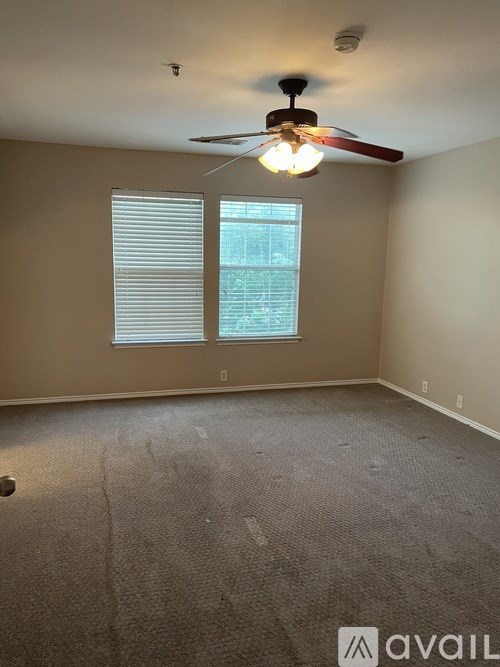 A room with a ceiling fan and a window with blinds.