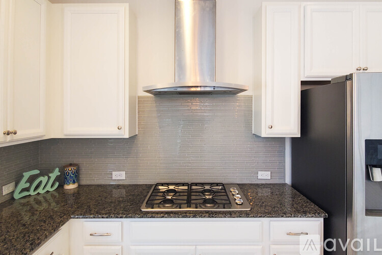 A kitchen with a stove top oven and a black refrigerator.