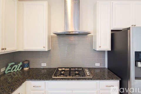 A kitchen with a stove top oven and a black refrigerator.