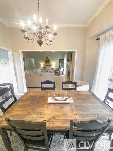 A wooden dining table with chairs and a chandelier in a room.