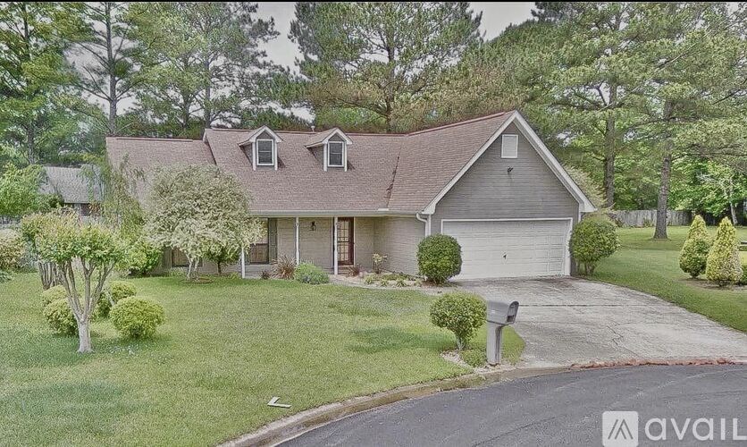 A house with a brown roof and a garage door is surrounded by greenery.