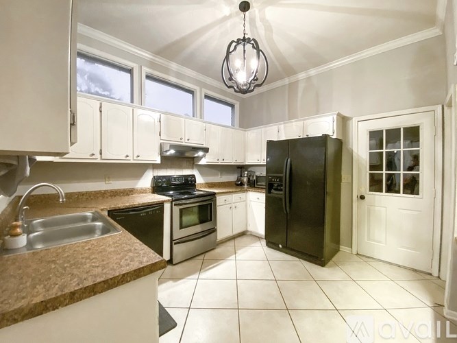 A kitchen with white cabinets and a black fridge.