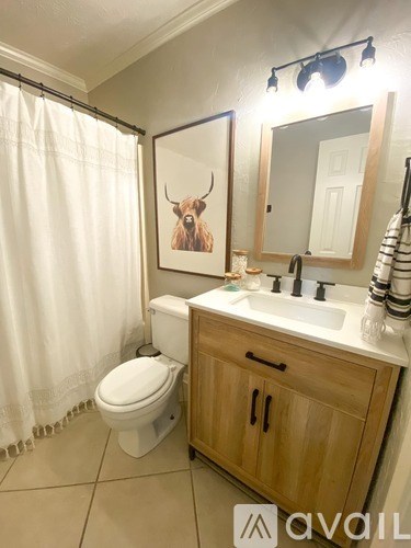 A bathroom with a toilet, sink, and a painting of a bull head on the wall.