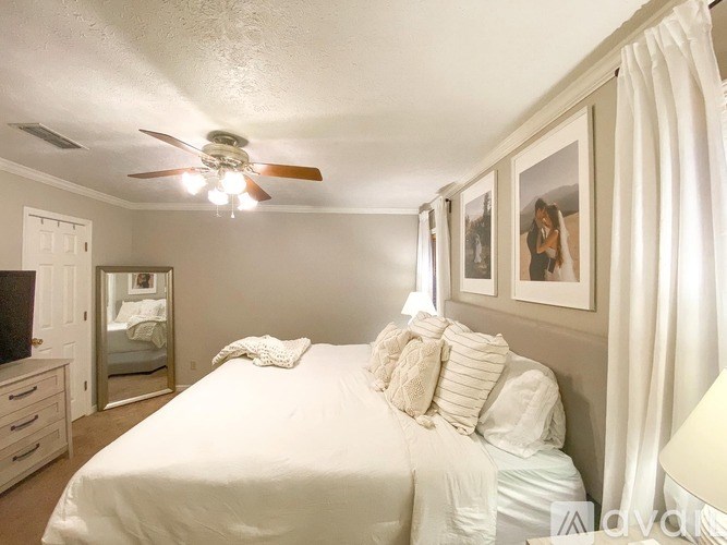 A bedroom with a large bed and a ceiling fan.