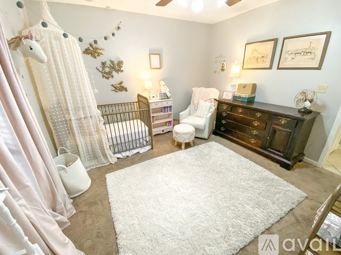 A baby nursery with a crib, rocking chair, and a dresser.