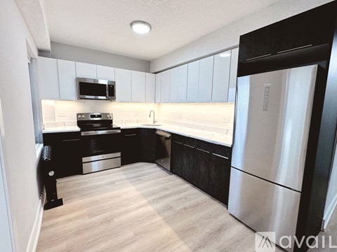 A kitchen with a stainless steel refrigerator and a microwave above the stove.