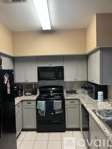 A kitchen with black appliances and white cabinets.