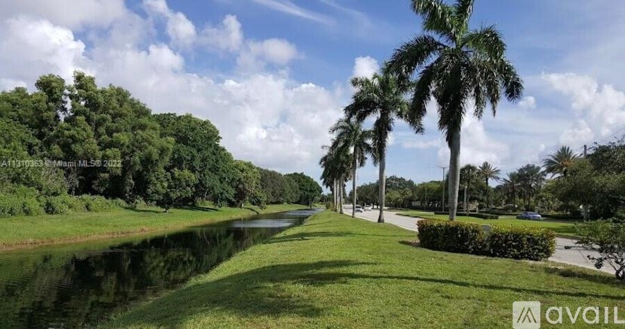 A canal with greenery on both sides under a blue sky.