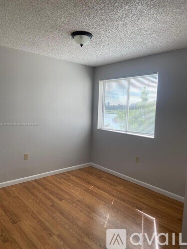 A room with wooden flooring and a window with blinds.