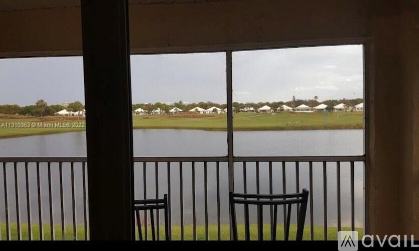 Two black chairs are placed on a balcony overlooking a body of water.