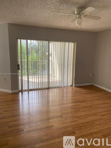 A room with wooden floors and a sliding glass door leading outside.