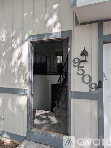A white building with a doorway and a number 9509 displayed on it.