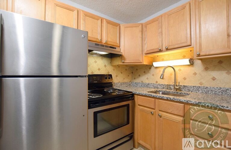 A kitchen with a stainless steel refrigerator and wooden cabinets.