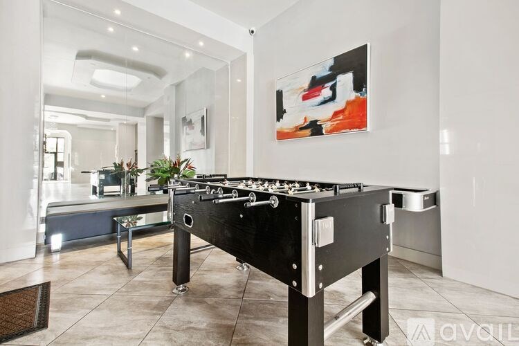 A foosball table is in the middle of a room with a painting on the wall.