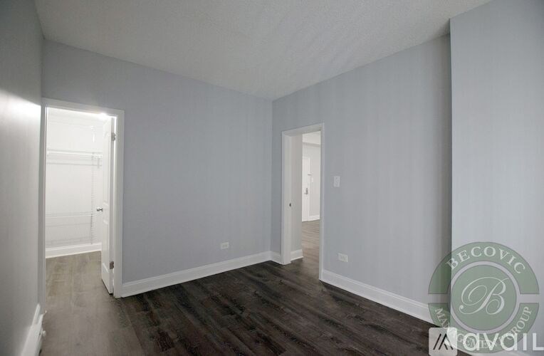 A spacious room with wooden flooring and white walls.