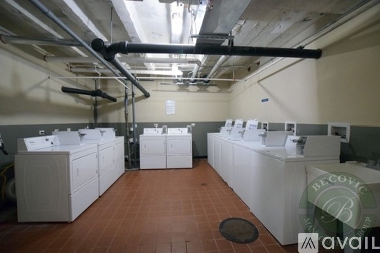 A row of white washing machines are lined up in a laundromat.