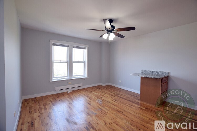 A room with a ceiling fan and wooden flooring.