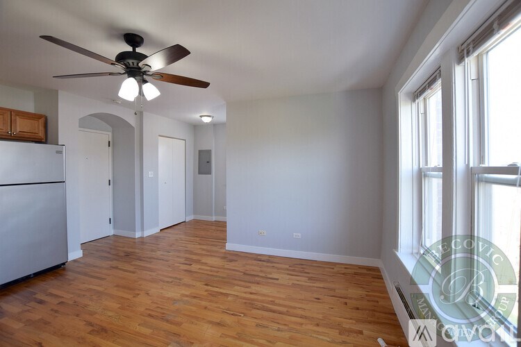 A room with a ceiling fan and wooden floors.