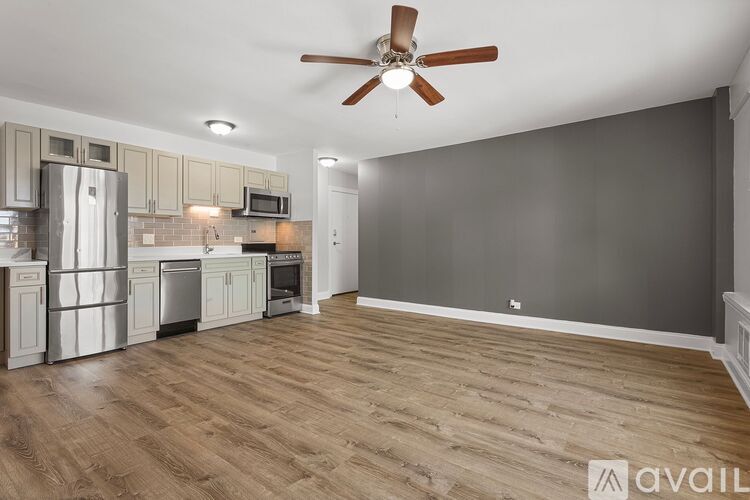 A kitchen with a refrigerator, microwave, oven, and a fan on the ceiling.