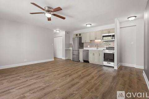 A spacious kitchen with a fan and wooden flooring.