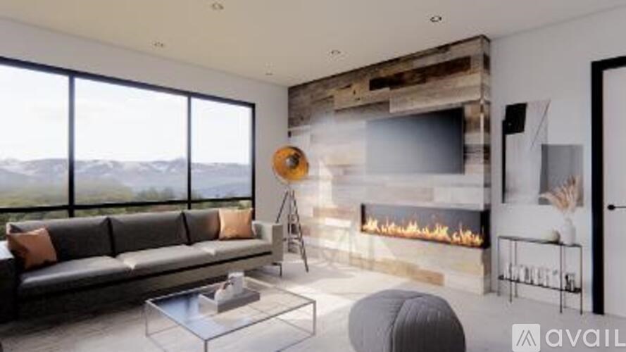 A modern living room with a fireplace and a large window overlooking the mountains.