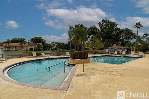 A large outdoor swimming pool surrounded by palm trees and lounge chairs.