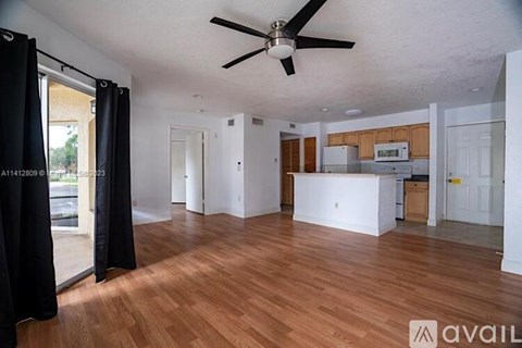A spacious living room with a ceiling fan and hardwood flooring.