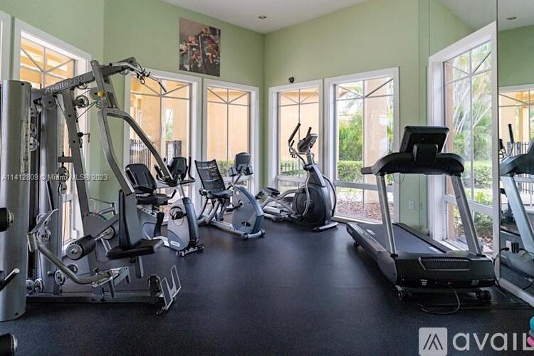 A gym with a variety of equipment including treadmills, elliptical machines, and weight machines.